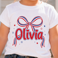 White t-shirt with a red, white, and blue bow design and the name 'Olivia' on a blurred background