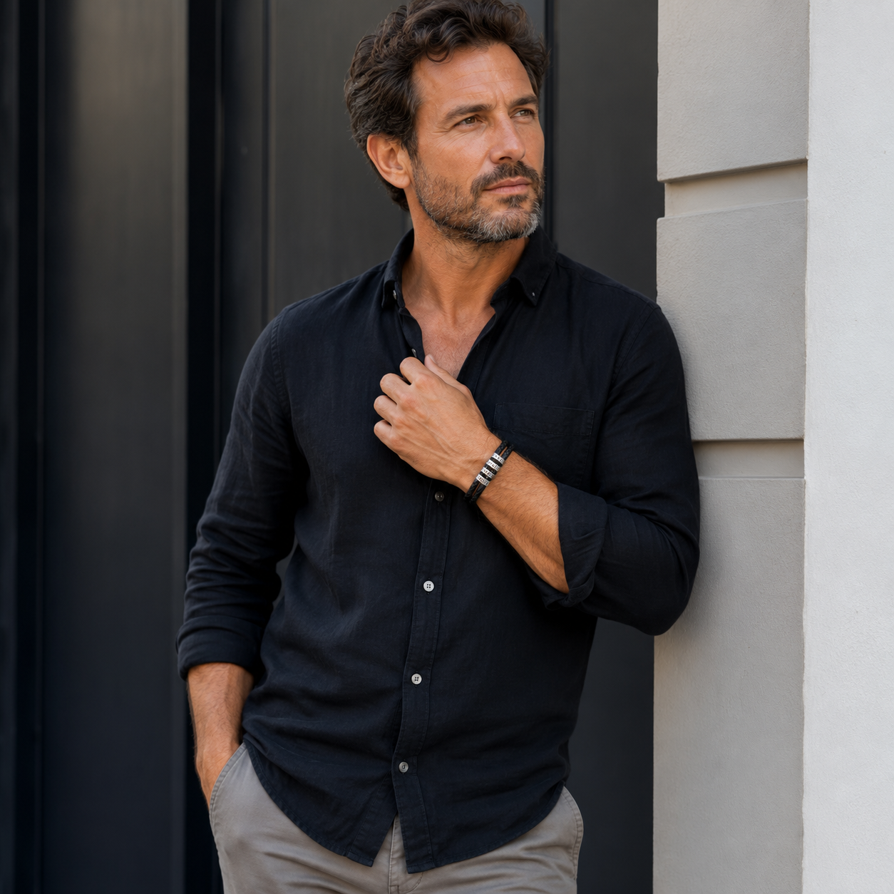 Man wearing a black shirt leaning against a wall