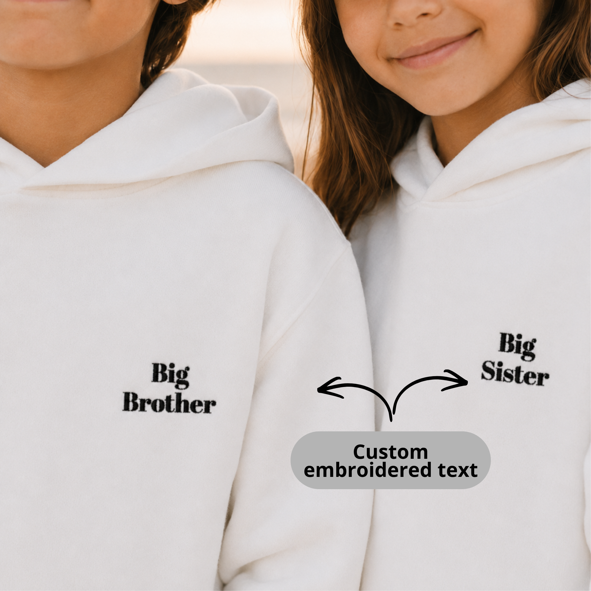 Two children wearing white hoodies with 'Big Brother' and 'Big Sister' text on a plain background.