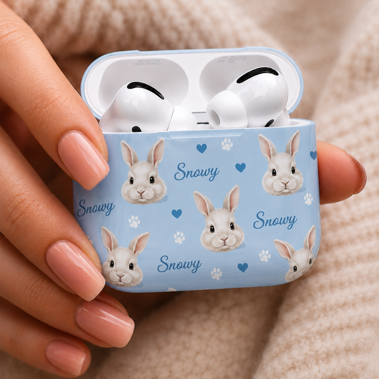 Wireless earbuds in a case with 'Snowy' rabbit design held by a hand.