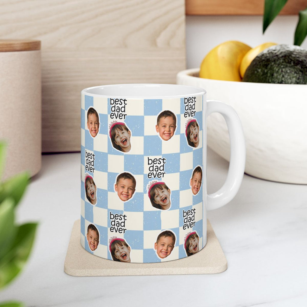 Mug with 'best dad ever' text and multiple small images of a child on a checkered background, placed on a coaster.