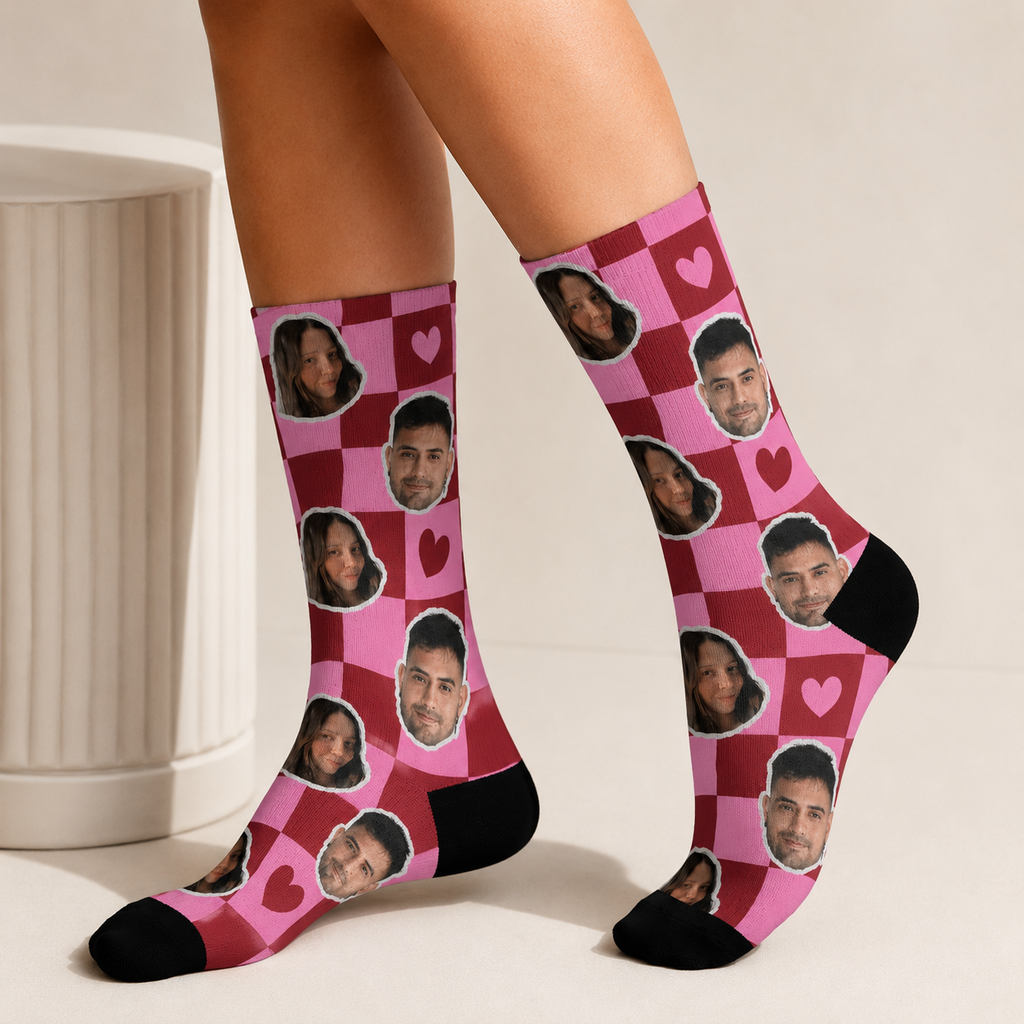Pink checkered socks with heart patterns and face prints worn by a person.