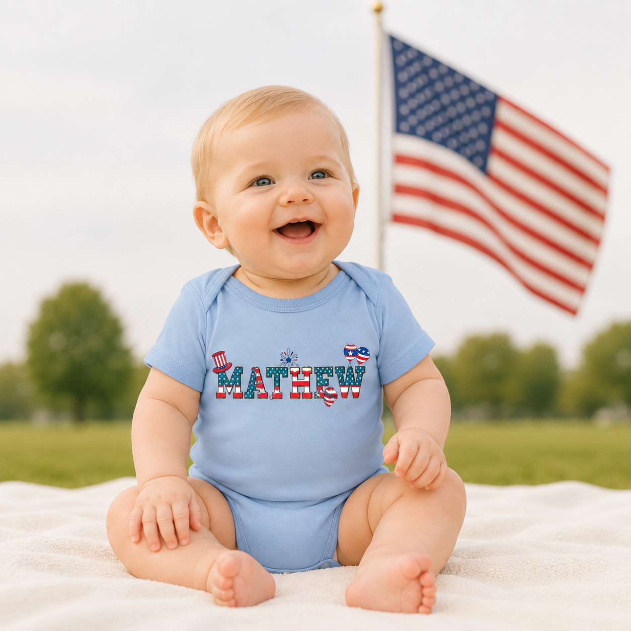 Baby wearing a blue onesie with 'MATHEW' printed on it, sitting outdoors with an American flag in the background.