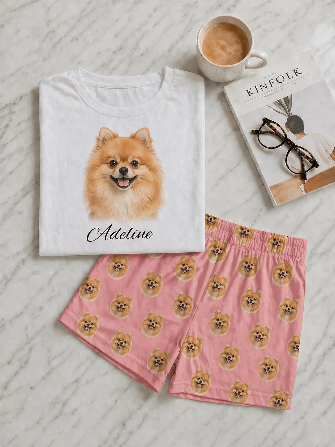 White t-shirt with a dog print and pink shorts with dog pattern on a textured surface.