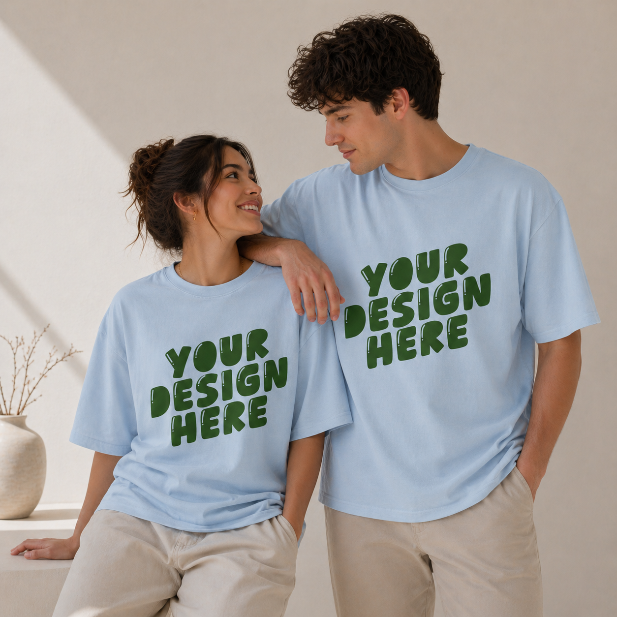 Two people wearing light blue t-shirts with 'Your Design Here' text.