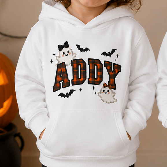 Two young children standing side by side wearing matching white hoodies with a custom 'NAME YOUR CHILD' graphic featuring the names 'ADDY' and 'ETHAN' in a spooky font with bats and a small ghost.