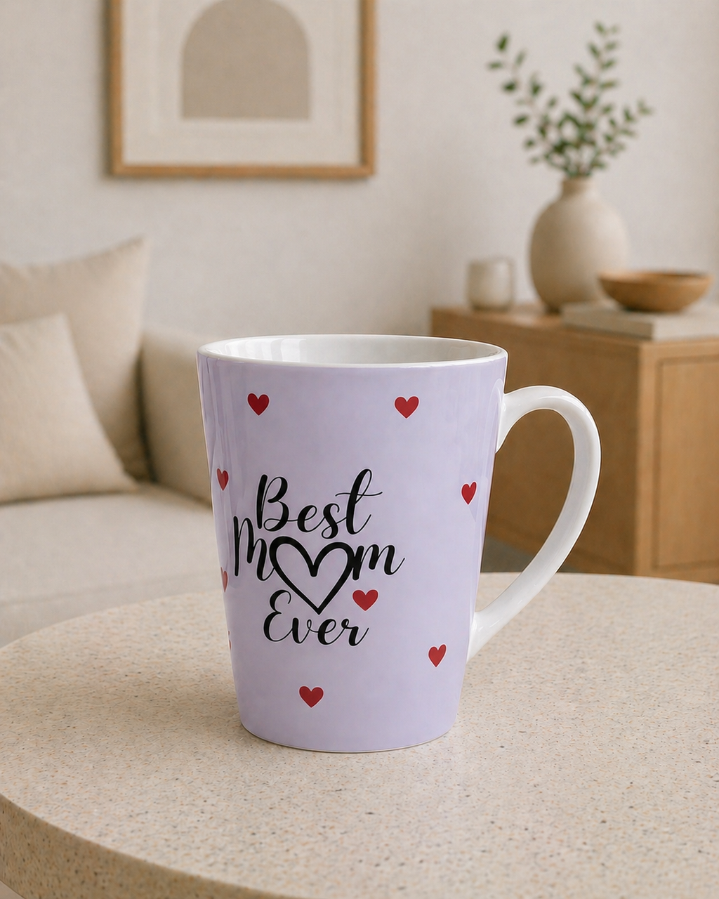 White mug with 'Best Mom Ever' text and red hearts on a table in a cozy living room.