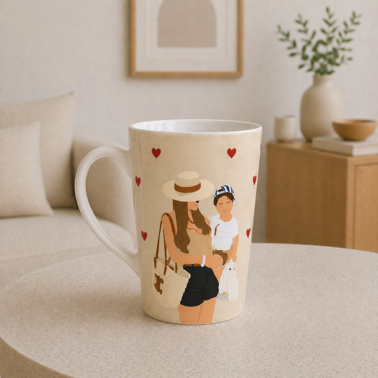 Beige mug with a design of a woman and child holding hands, surrounded by hearts, on a beige surface.