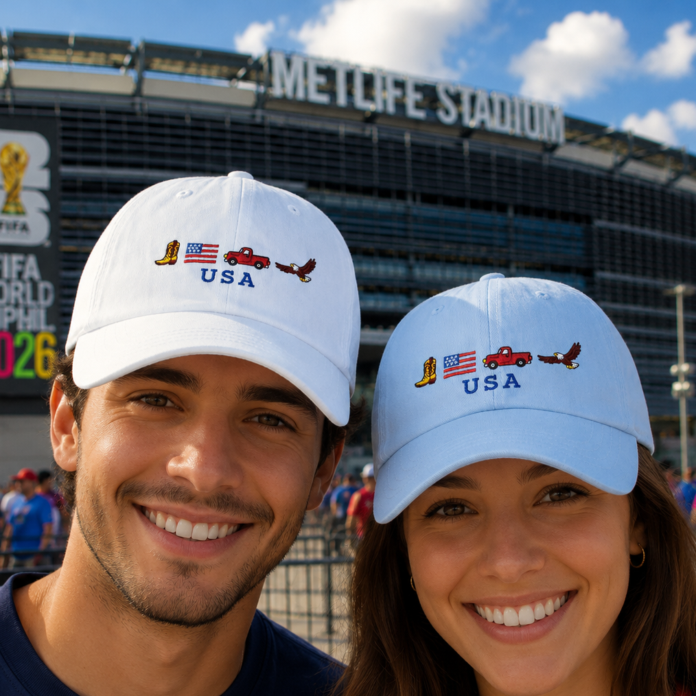 Two people wearing USA-themed caps in front of Metlife Stadium with FIFA World Cup 2026 signage.