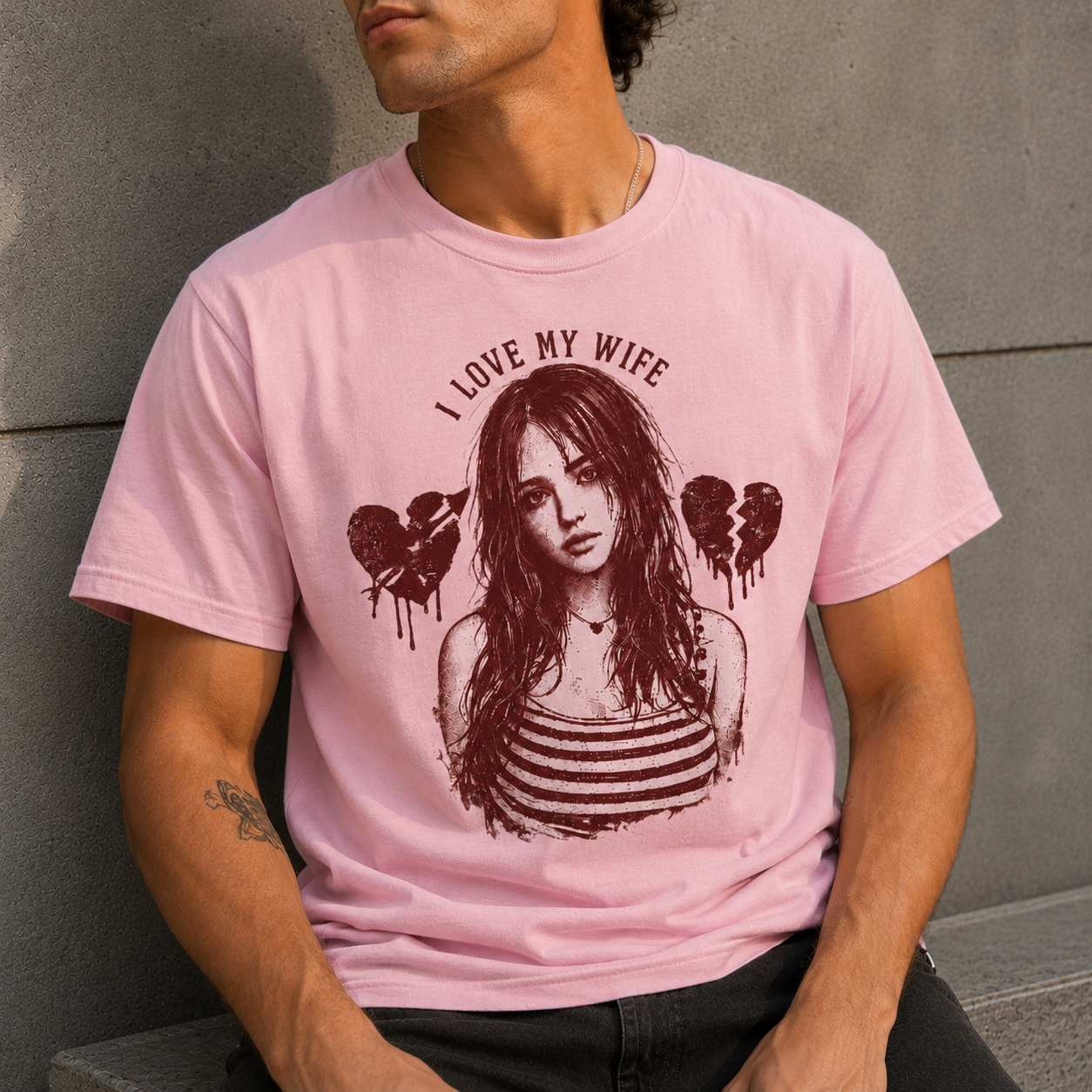 Person wearing a pink t-shirt with a graphic design and text against a gray wall.