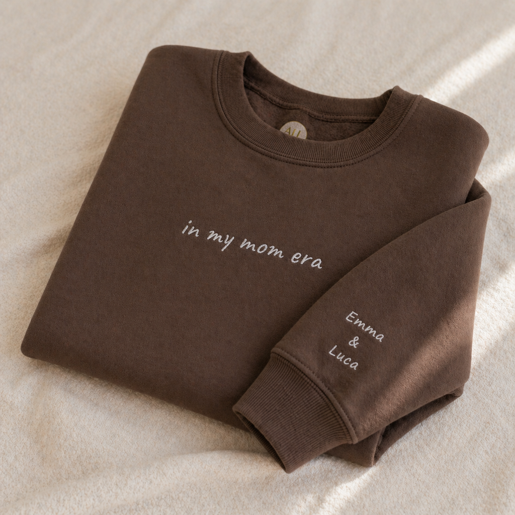 Folded brown sweatshirt with text on a beige surface