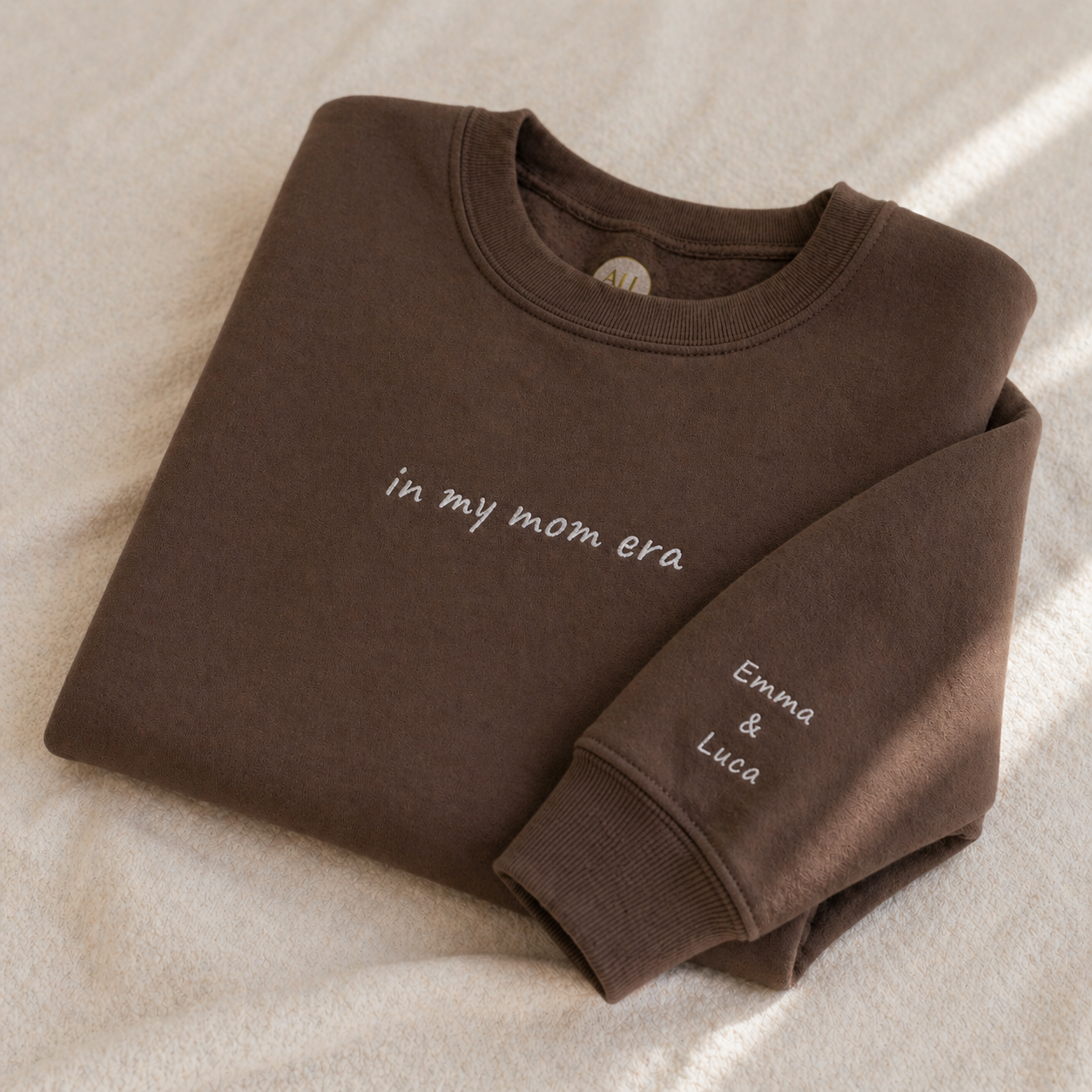 Folded brown sweatshirt with text on a beige surface