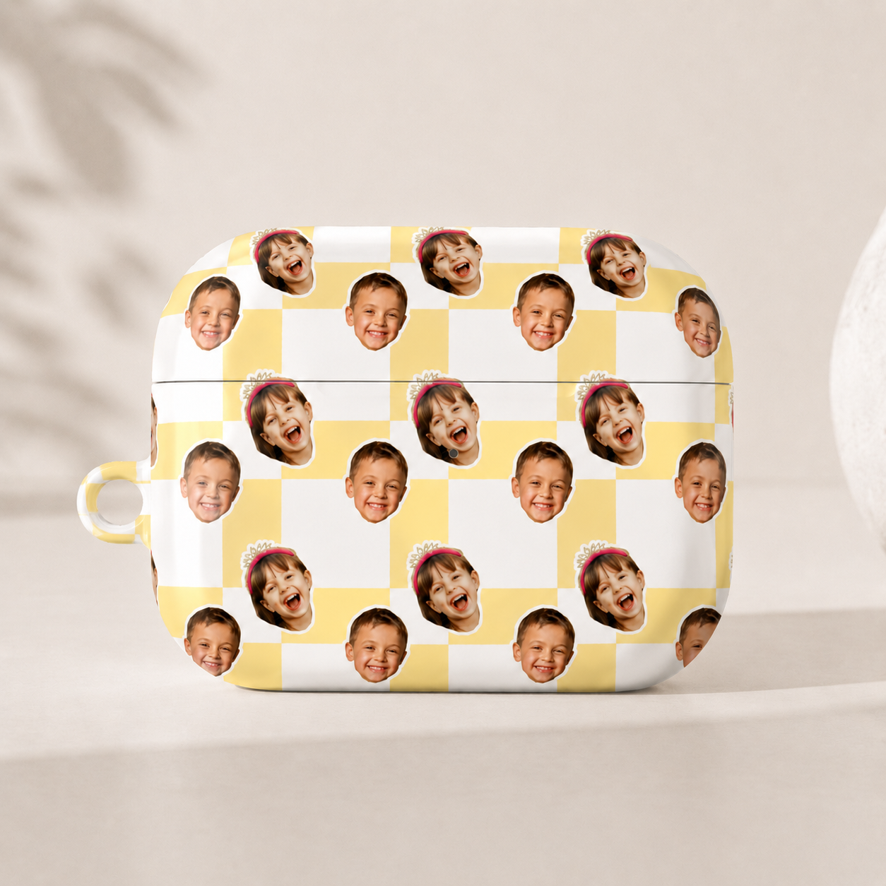 AirPods case with a checkered pattern of children's faces on a neutral background