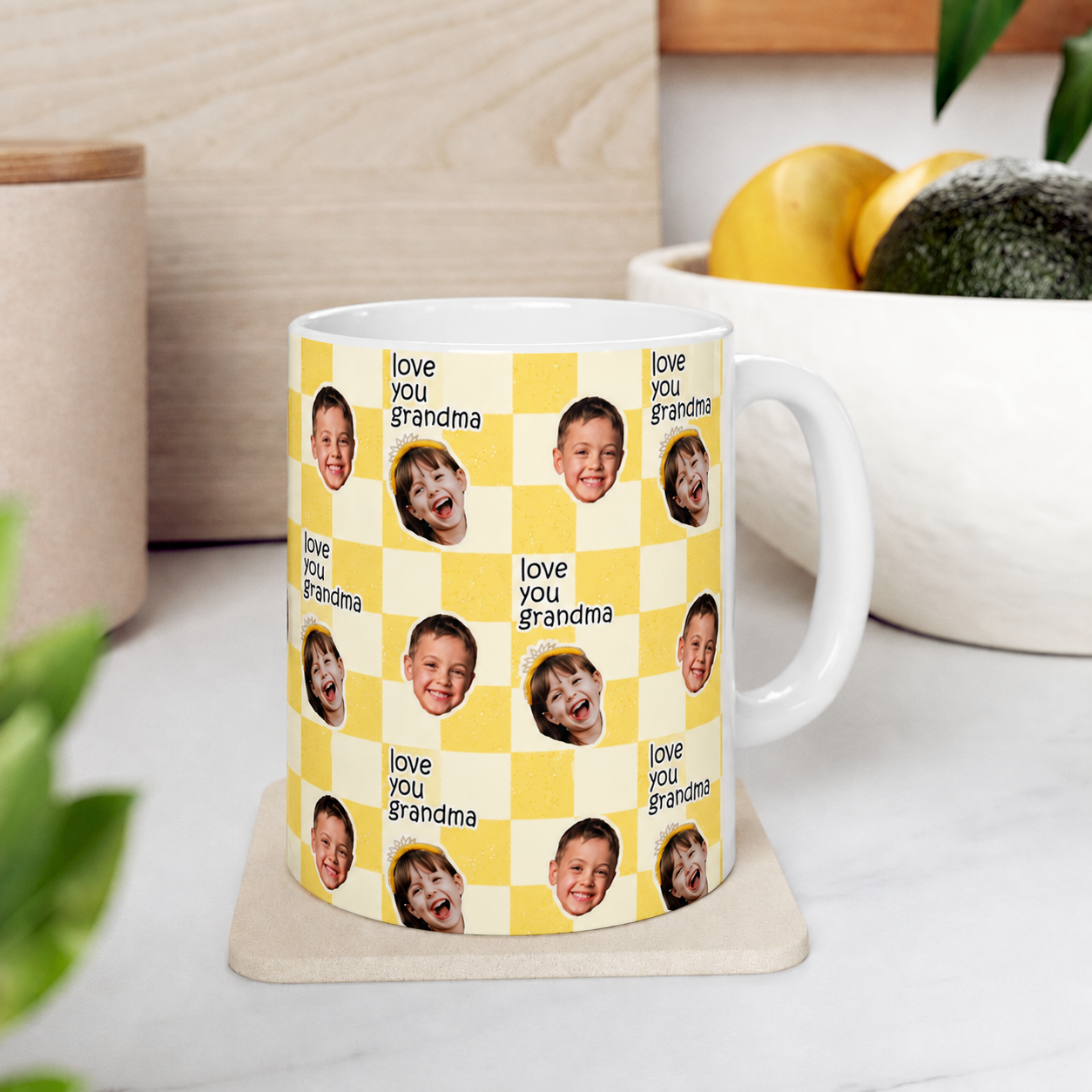 Mug with 'love you grandma' text and multiple photos of a child on a yellow checkered background, placed on a white surface.